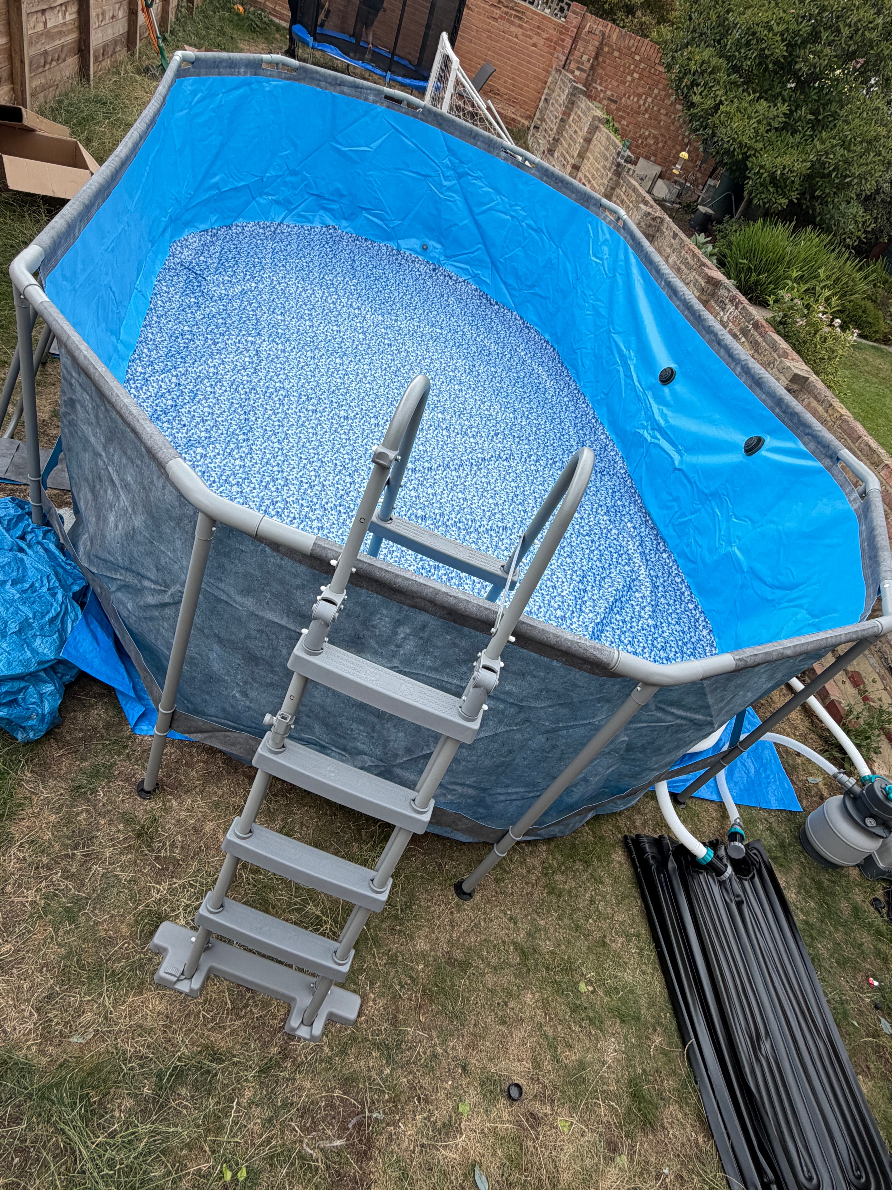Large above-ground swimming pool assembled and filled in garden