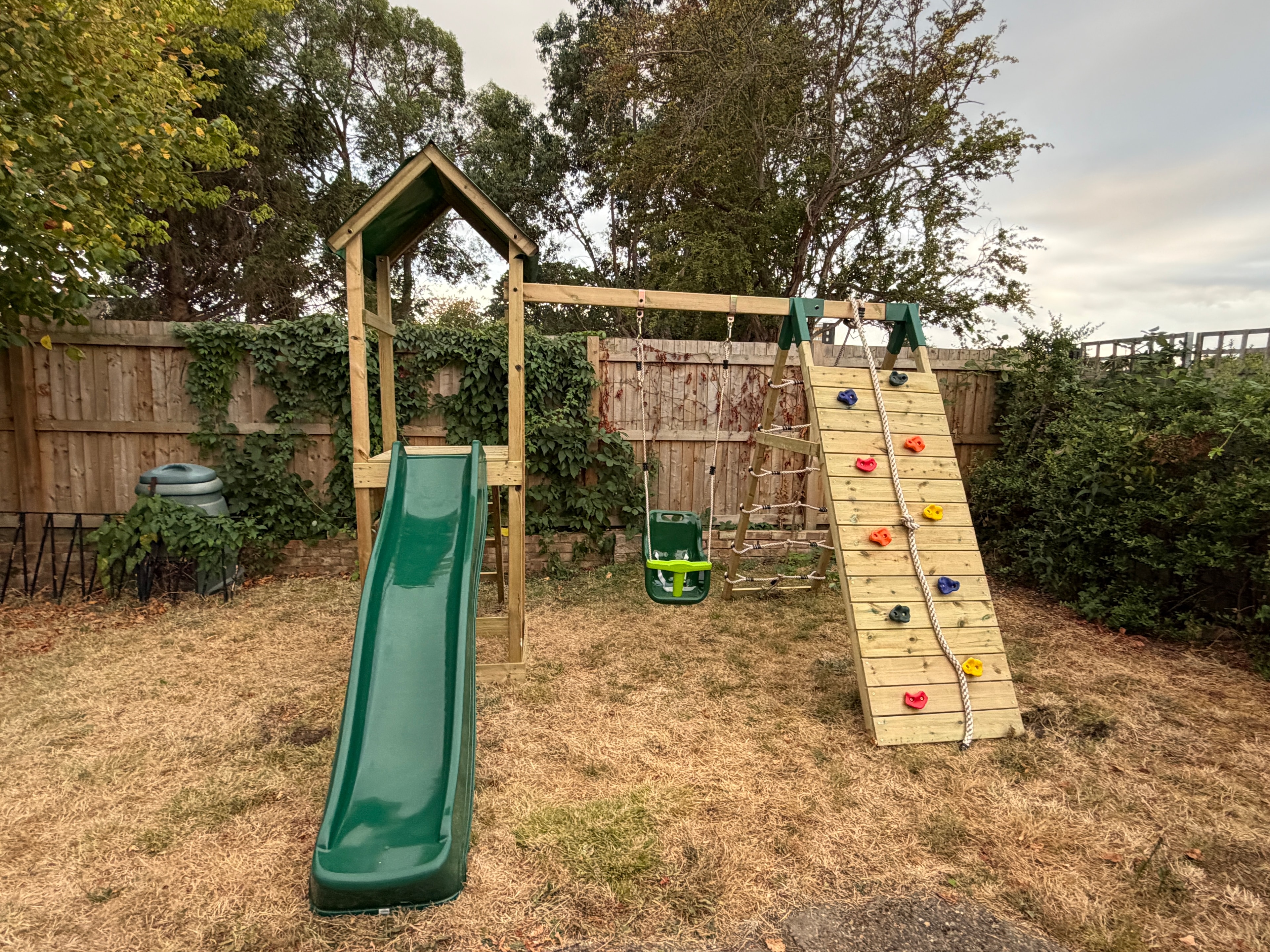 Wooden climbing frame with rock wall panel and slide assembled
