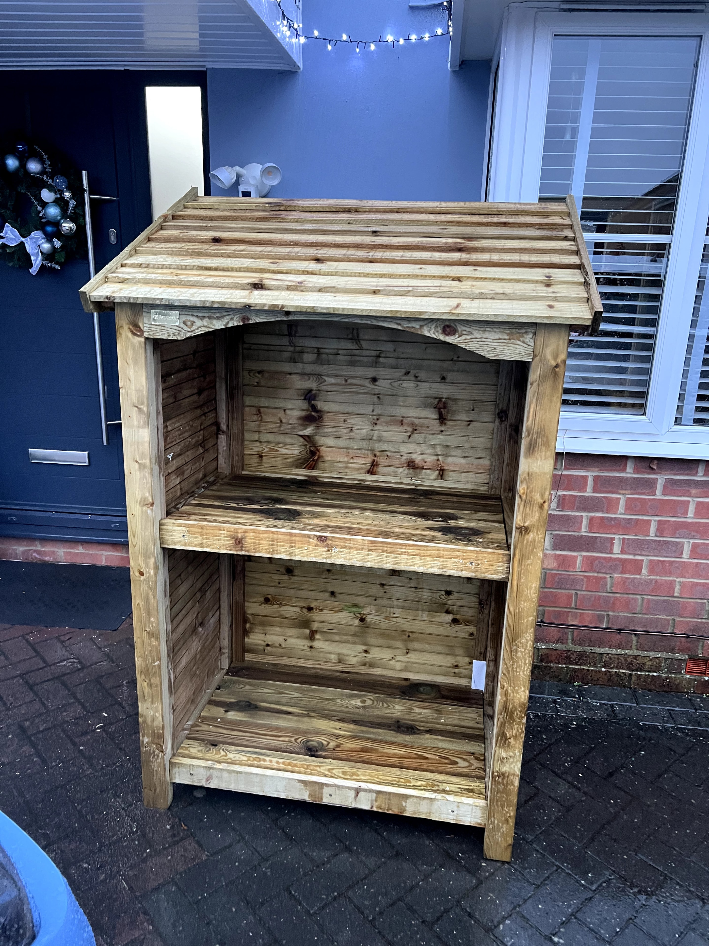 Wooden log store with shelves assembled outside front door